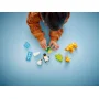 Kind speelt met LEGO pinguïn- en leeuwfiguren, kleurrijke stenen en groene elementen op blauwe achtergrond Kind speelt met LEGO pinguïn- en leeuwfiguren, kleurrijke stenen en groene elementen op blauwe achtergrond